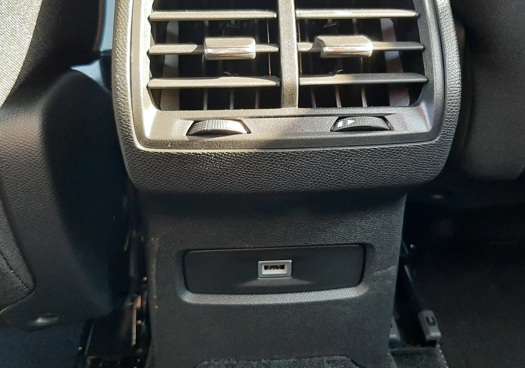 Gros plan sur la sortie d'air arrière et prise USB noire du Citroën C4 blanc Okenite, intérieur en textile sombre.