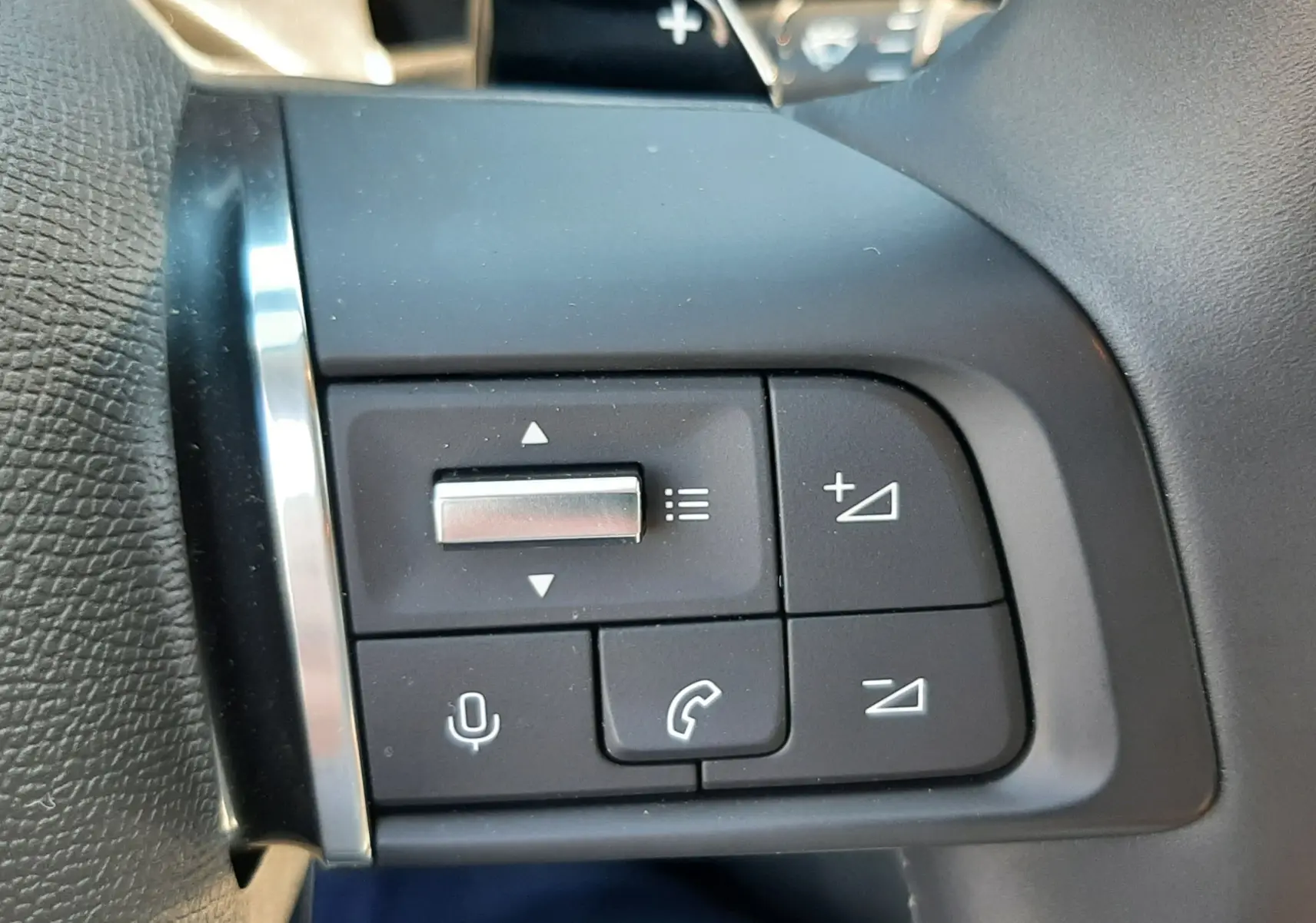 Gros plan sur les commandes au volant côté gauche du Citroën C4 blanc Okenite, avec boutons de volume et appel.