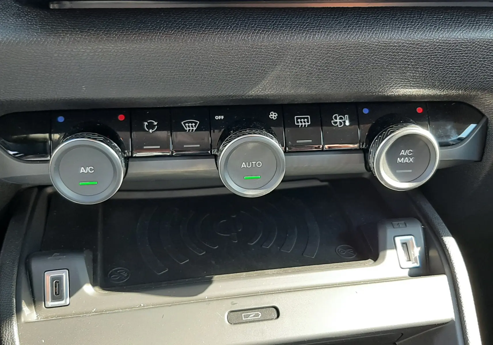 Vue rapprochée de la console centrale noire du Citroën C4 2025, montrant les commandes de climatisation avec trois boutons ronds.