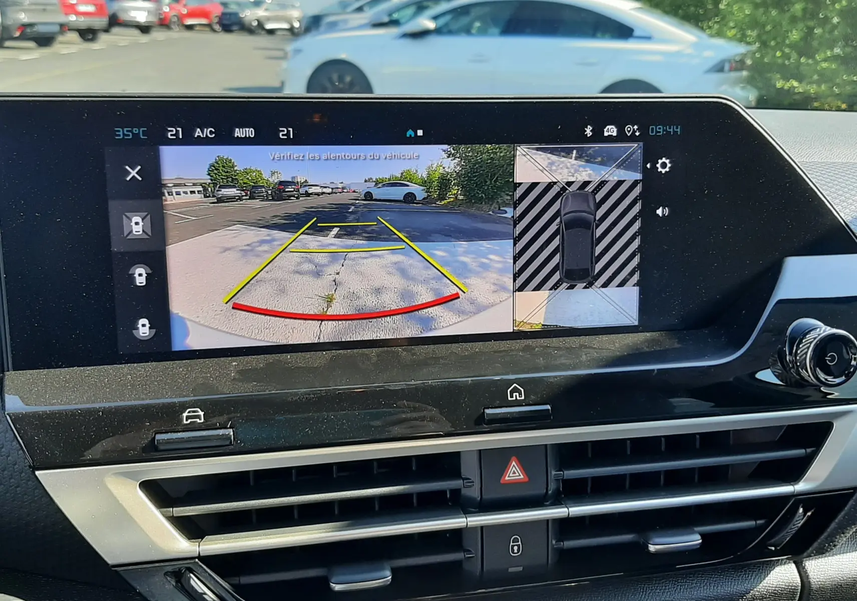 Écran intérieur montrant la caméra de recul avec vue arrière d’une Citroën C4 blanche garée en extérieur.