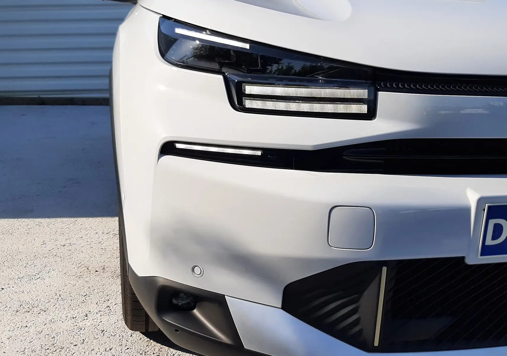 Vue avant droite d'une Citroën C4 blanche Okenite, mettant en valeur ses phares LED distinctifs et son pare-chocs moderne.