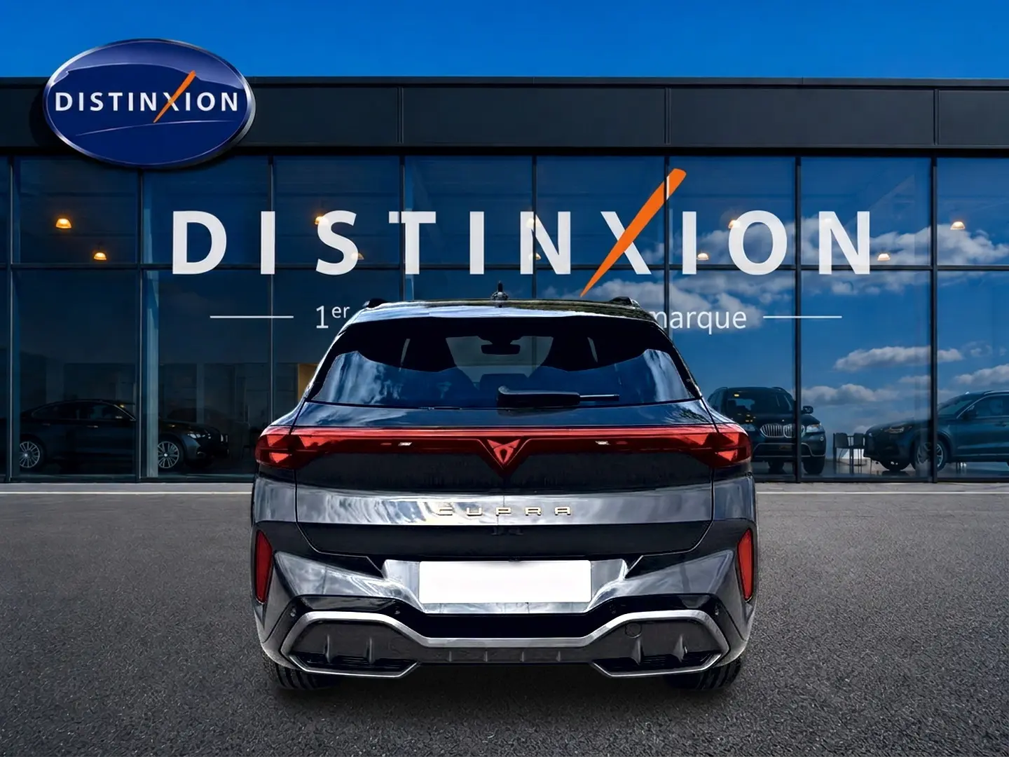 Vue arrière d'un CUPRA TERRAMAR gris timanfaya avec feux LED et logo distinctif rouge, devant un showroom Distinxion.