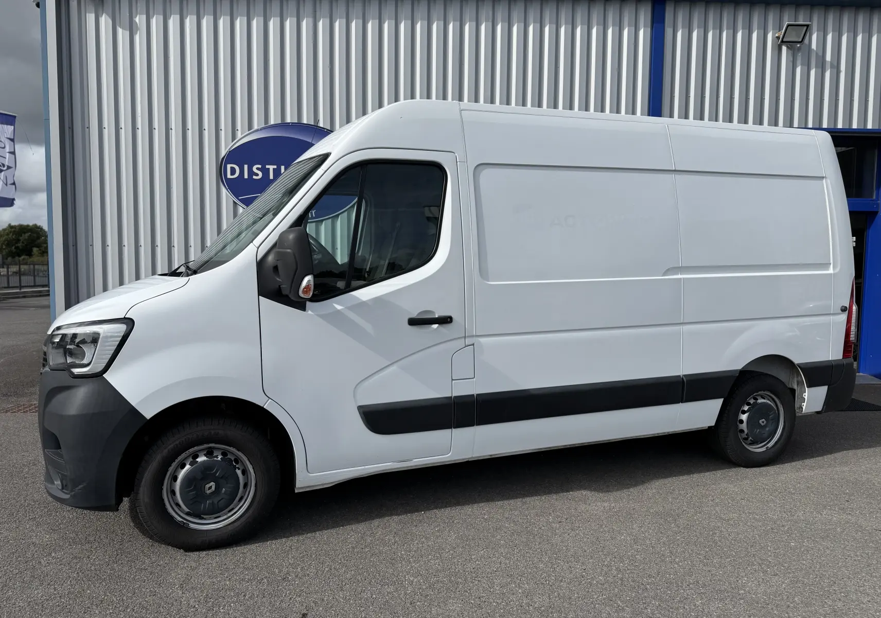Renault Master blanc vu de profil côté gauche, fourgon utilitaire avec bande noire sur la carrosserie.