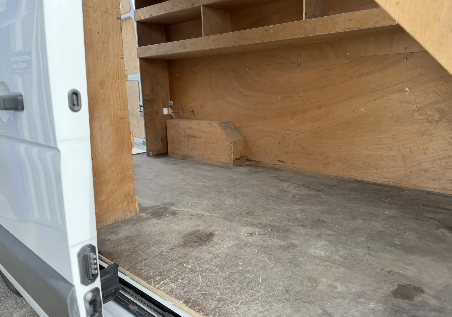 Intérieur du Renault Master blanc vu de la porte latérale ouverte, montrant l'espace de chargement en bois.