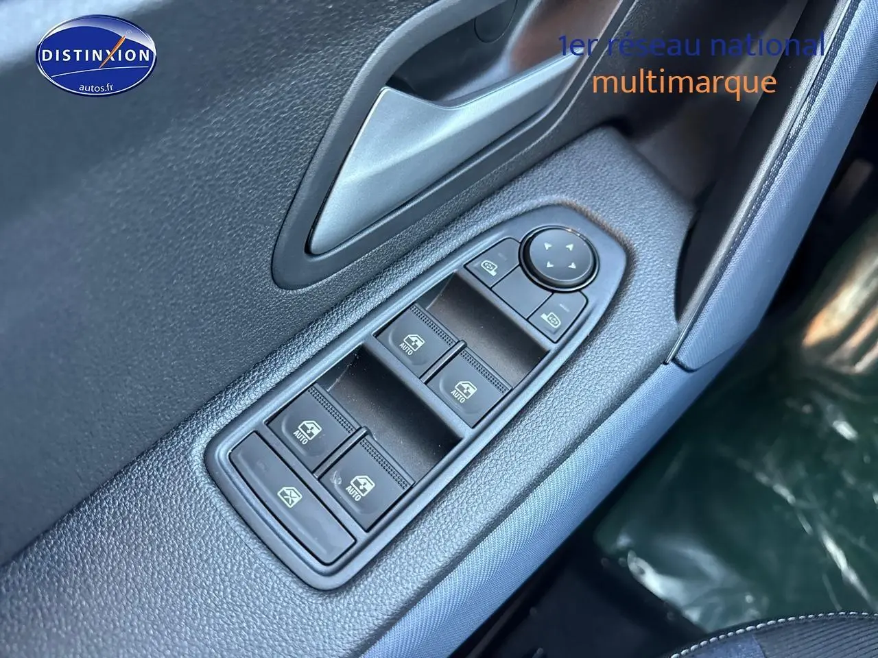 Gros plan sur les commandes des vitres électriques côté conducteur du Dacia Duster gris schiste, avec bouton de réglage des rétroviseurs.