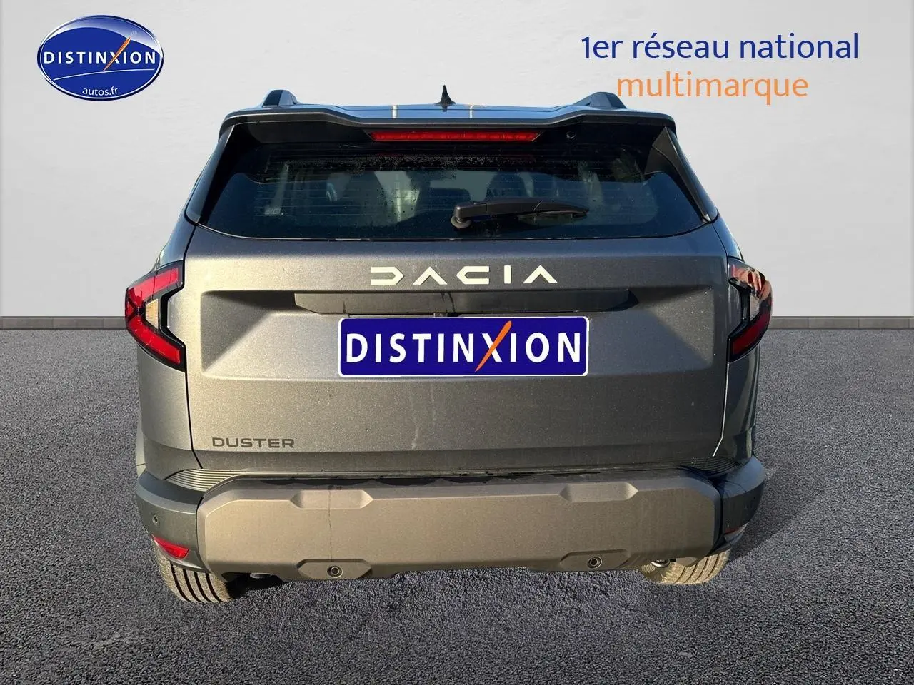 Vue arrière d'un Dacia Duster gris schiste 2025 avec feux LED et hayon noir mat, stationné sur sol goudronné.