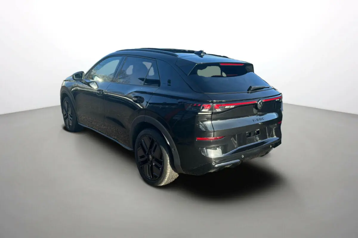 Volkswagen T-Roc noir ebène en 3/4 arrière droit, avec jantes alu noires et feux arrière LED reliés.