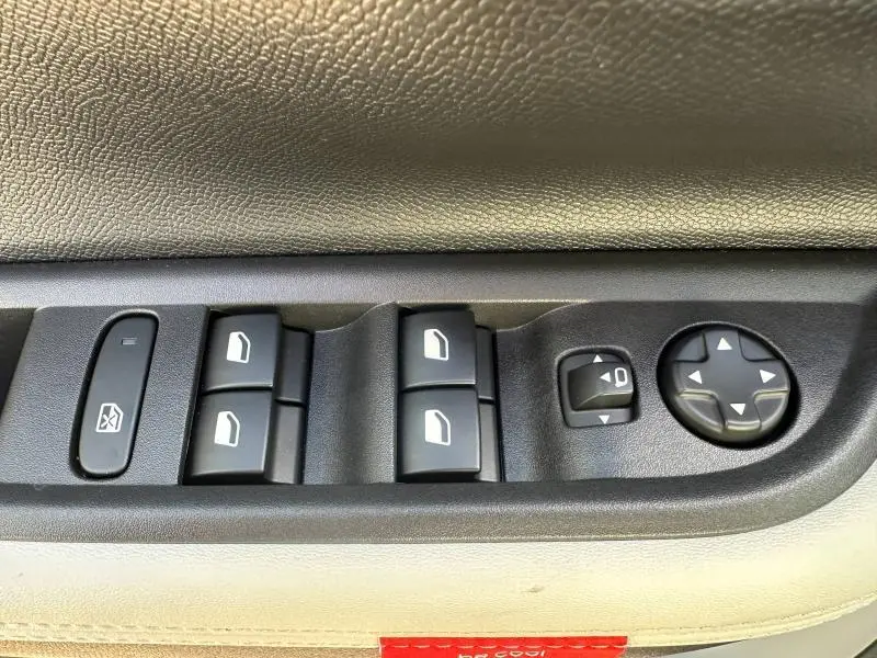 Gros plan sur les commandes des vitres et rétroviseurs côté conducteur d'une Citroën C3 Aircross noire.