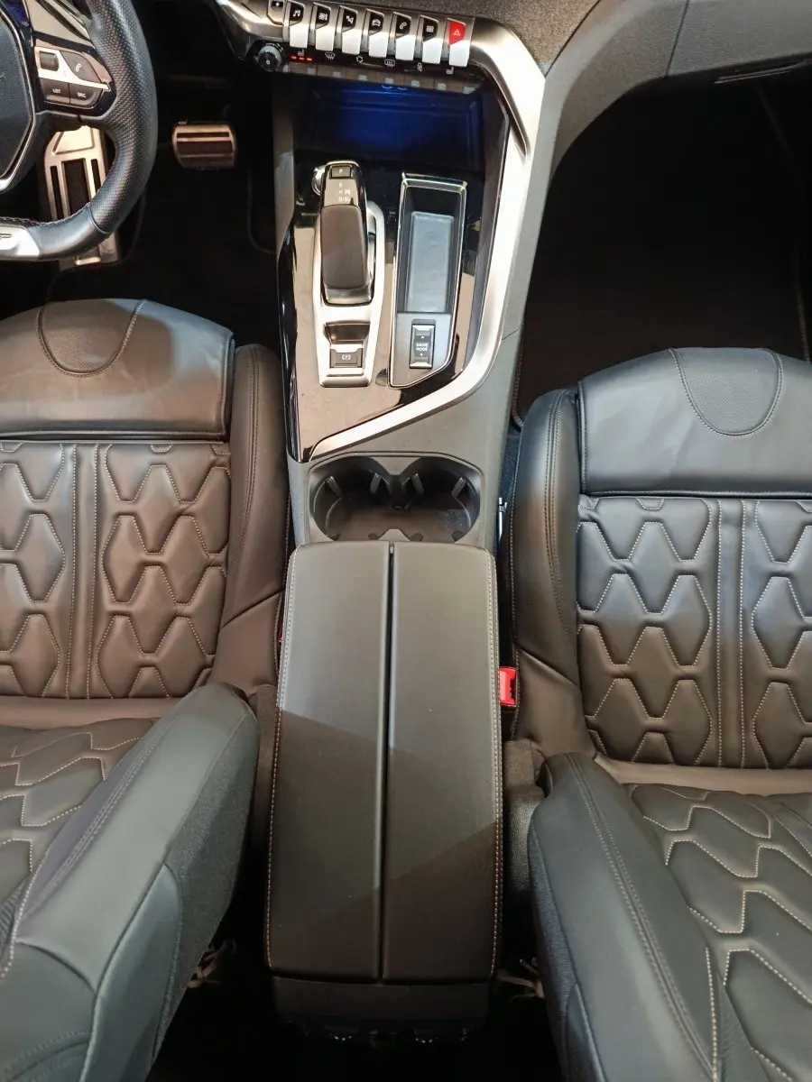 Vue plongeante sur la console centrale et les sièges en cuir noir du Peugeot 3008 Hybrid 225 GT Pack.