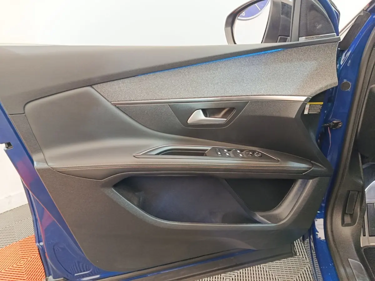 Vue intérieure côté gauche de la porte avant bleue du Peugeot 3008 avec commandes des vitres et poignée argentée.