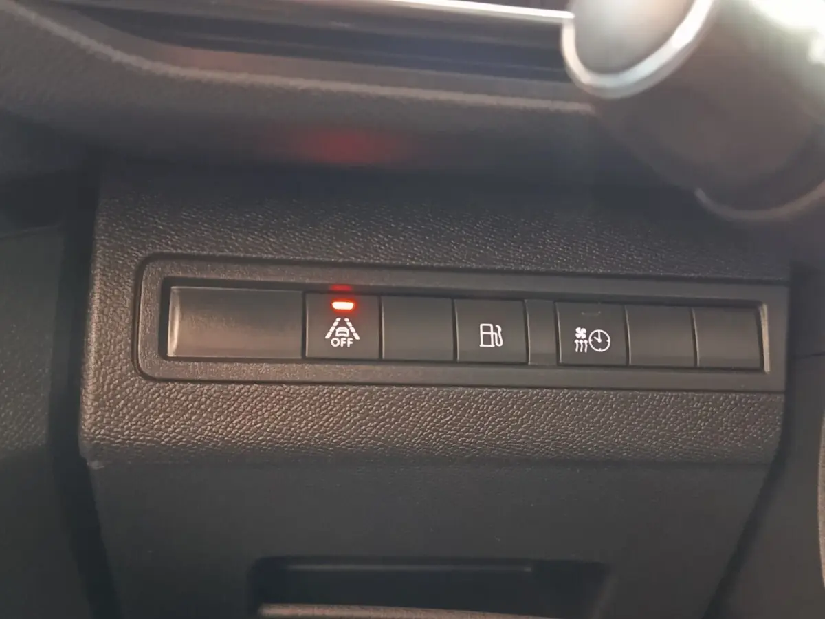 Gros plan sur les boutons de commande noirs du tableau de bord du Peugeot 3008 bleu, avec témoin rouge allumé.