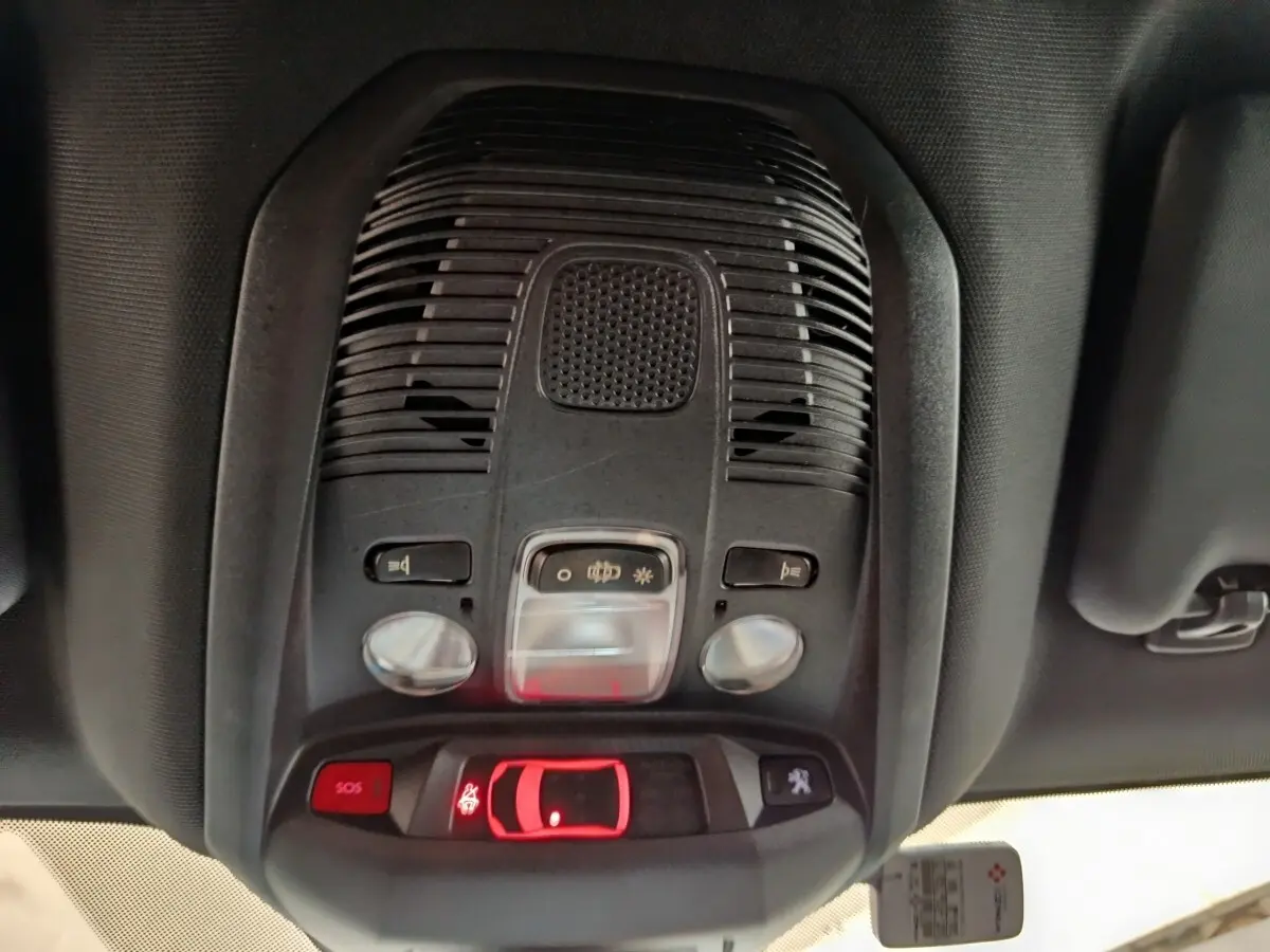 Vue intérieure du plafonnier avant du Peugeot 3008 bleu hybride rechargeable, avec commandes d’éclairage et bouton SOS.