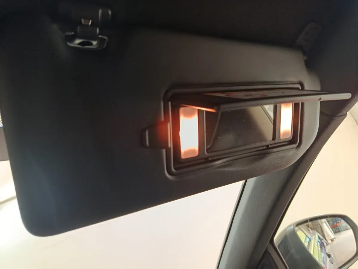 Détail du miroir de courtoisie éclairé sur le pare-soleil côté conducteur intérieur d’un Peugeot 3008 bleu.