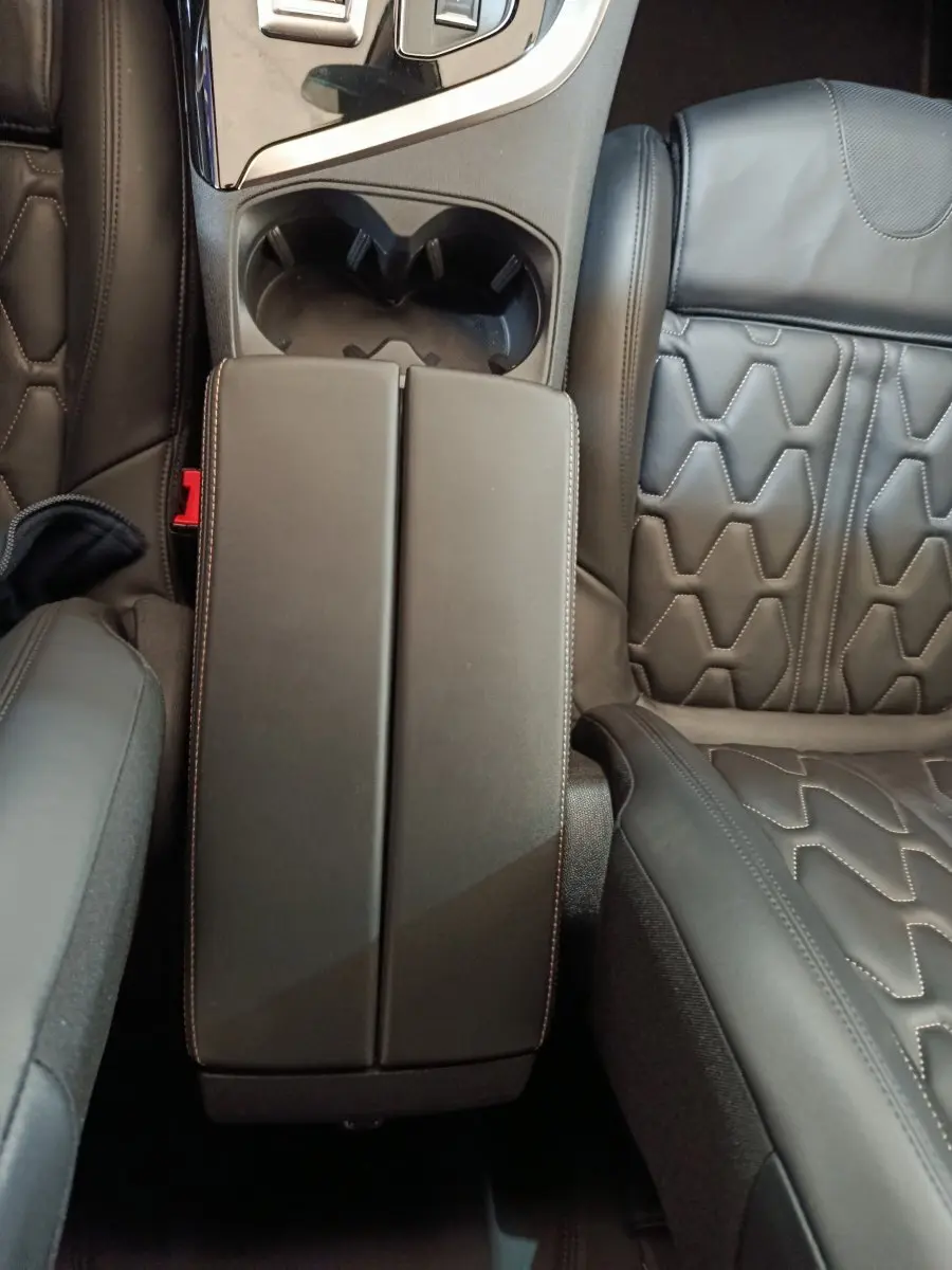 Vue plongeante sur l'accoudoir central et les sièges en cuir noir au motif hexagonal du Peugeot 3008 GT Pack hybride rechargeable.