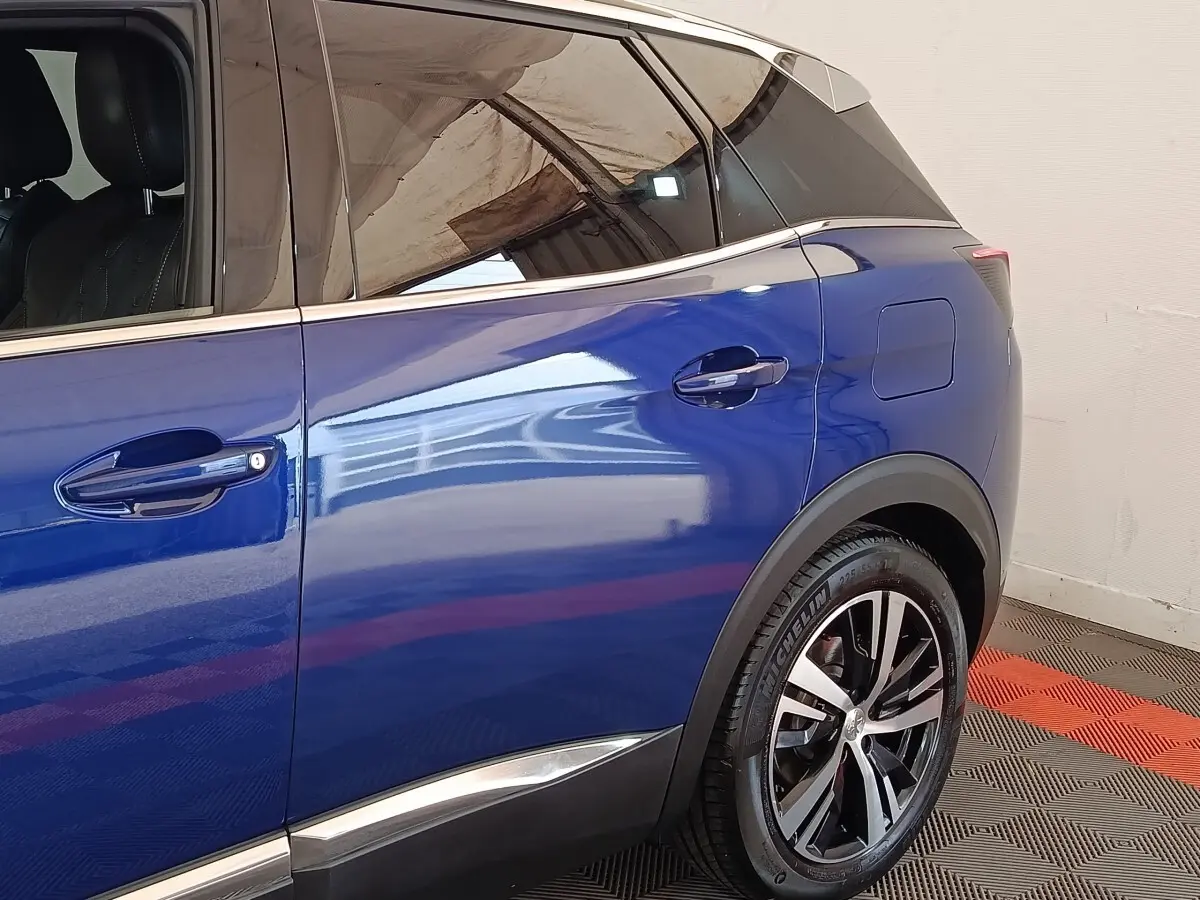 Vue côté droit arrière du Peugeot 3008 bleu hybride rechargeable, mettant en valeur la jante alliage et la trappe de recharge.