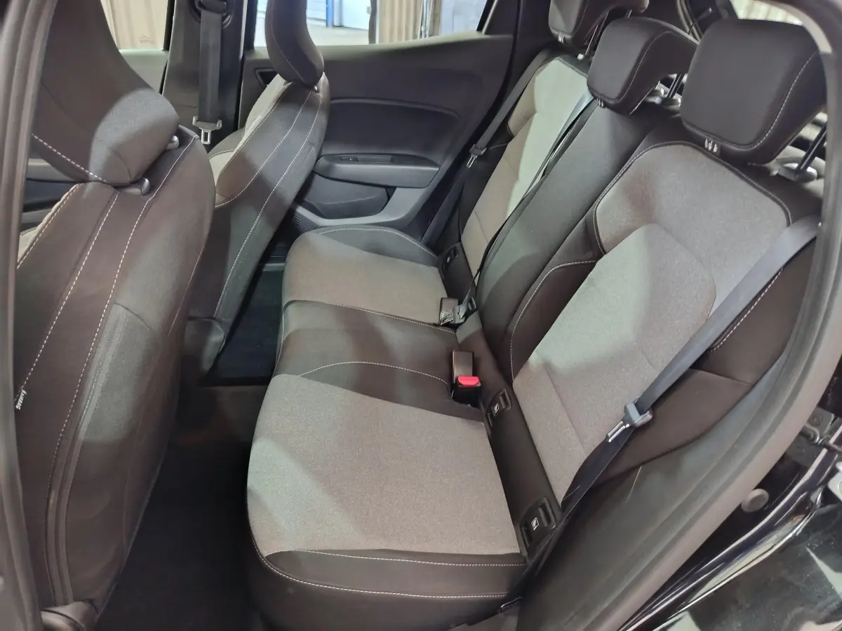 Vue côté droit sur l'intérieur arrière de la Renault Clio noire, montrant la banquette bi-ton gris et noir avec ceintures de sécurité.