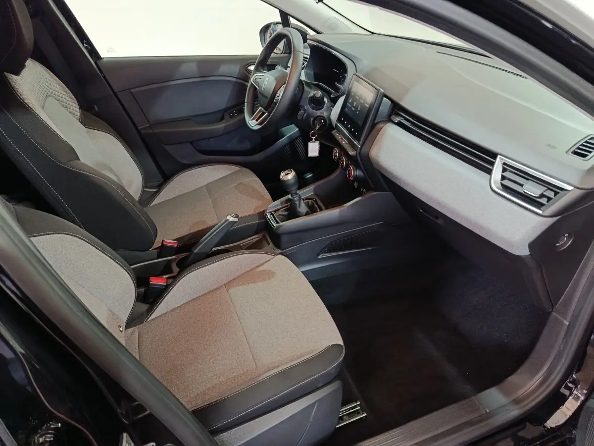 Vue intérieure côté conducteur de la Renault Clio Evolution Blue dCi 100 2025, sièges tissu gris et tableau de bord moderne.