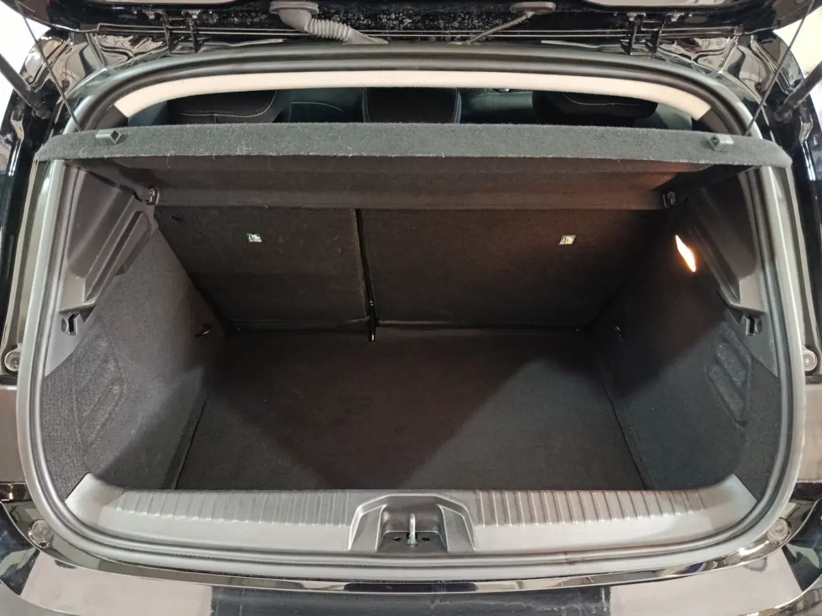 Coffre ouvert vu de l'arrière d'une Renault Clio noire 2025, montrant l'espace de chargement vide et l'éclairage intérieur.