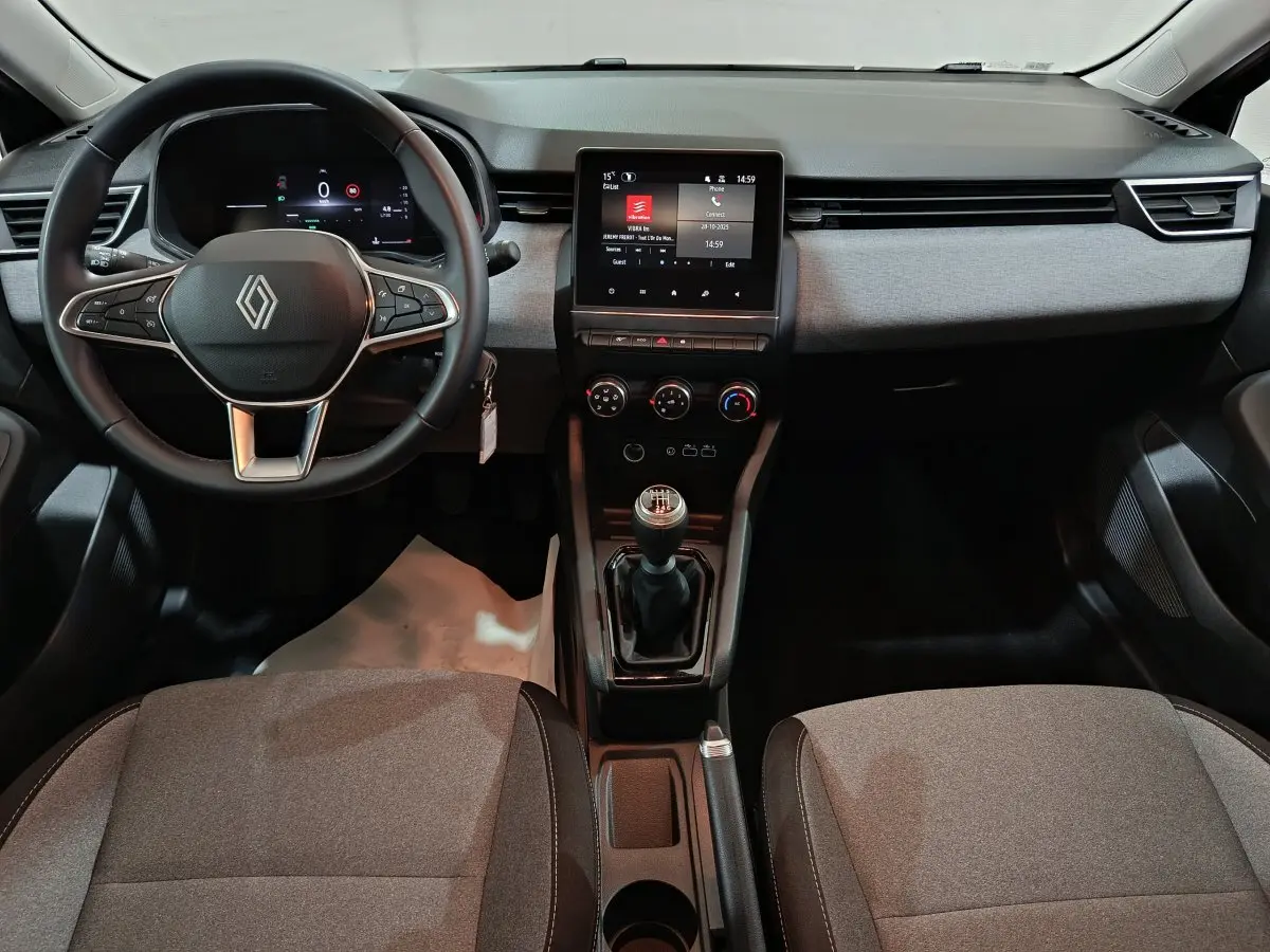 Vue intérieure frontale de la Renault Clio noire 2025 montrant le volant cuir, écran tactile central et levier de vitesse manuel.
