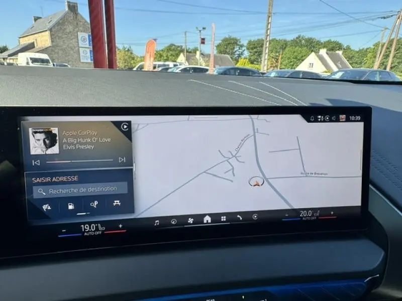 Vue intérieure du tableau de bord du BMW X3 xDrive20 2024 avec écran tactile large affichant navigation et musique, finition Alcantara noire.