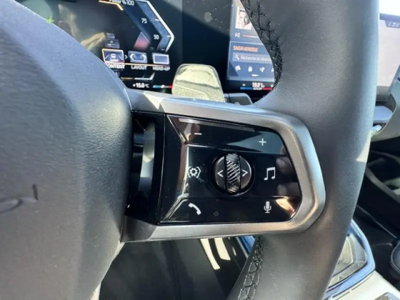 Gros plan sur les commandes multifonctions noires du volant cuir du BMW X3 xDrive20 M Sport 2024.