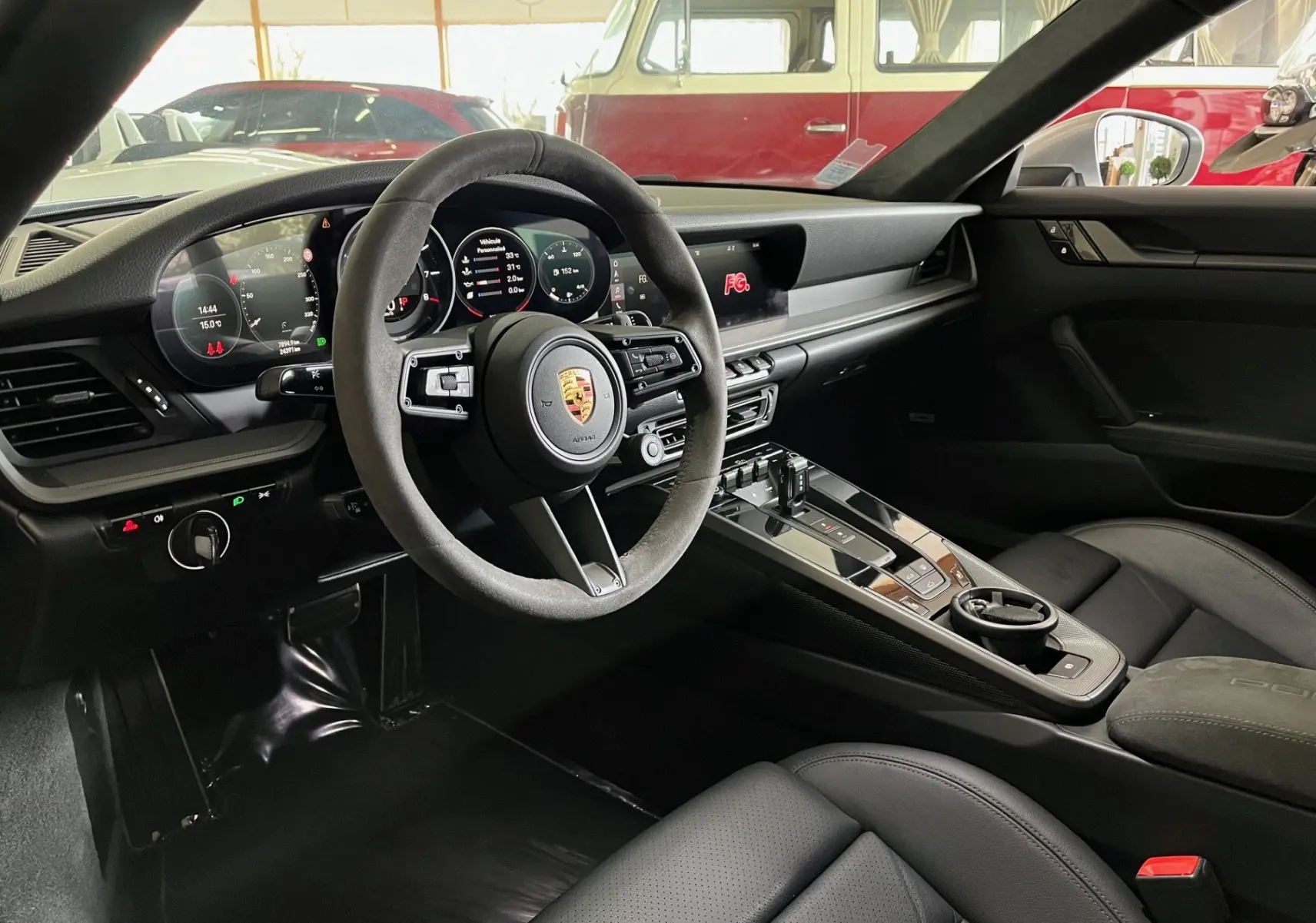 Intérieur noir de la Porsche 911 (992) Coupé 2019, vue côté conducteur sur le volant Alcantara et tableau de bord digital.