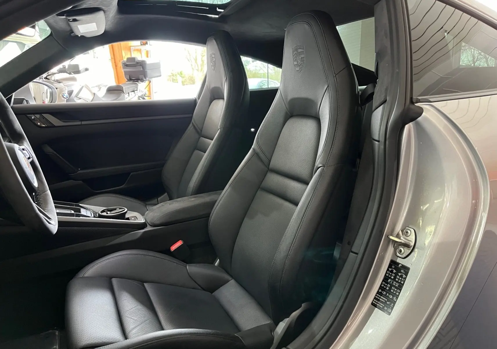 Vue intérieure côté conducteur de la Porsche 911 Carrera S 2019 avec sièges sport cuir noir et toit ouvrant panoramique.