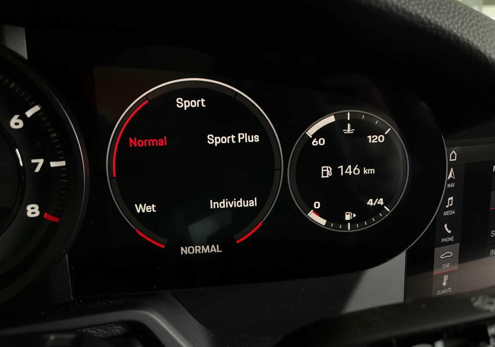 Tableau de bord numérique de Porsche 911 (992) affichant les modes de conduite et l'autonomie restante à 146 km.