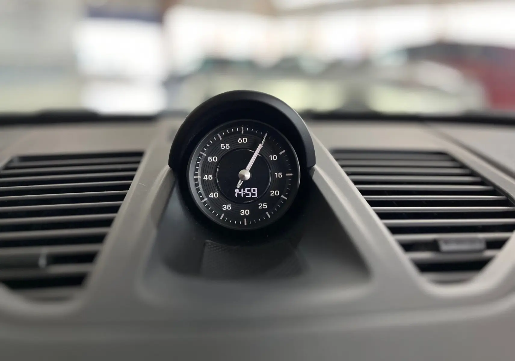 Gros plan sur l'horloge centrale du tableau de bord noir d'une Porsche 911 Carrera S 2019, finition Alcantara.