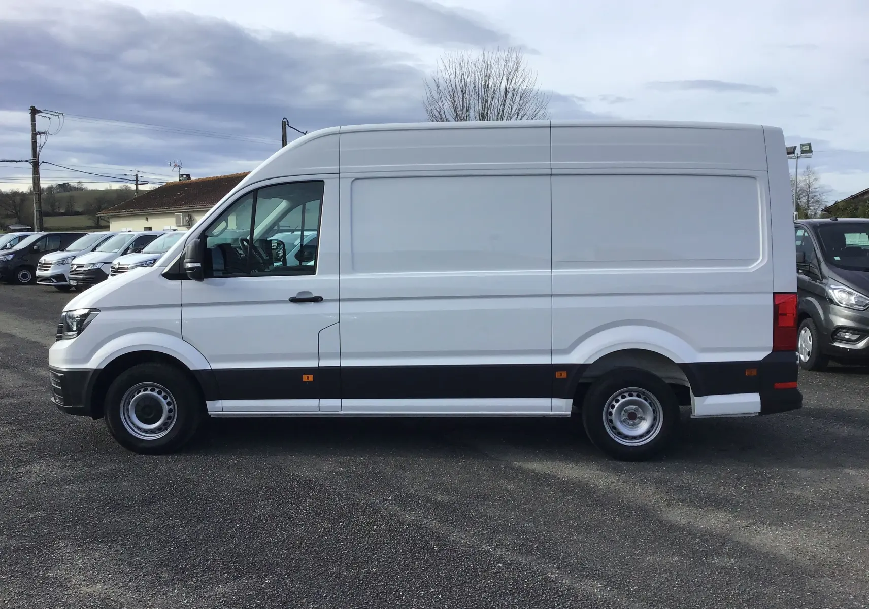 Vue de profil côté gauche d’un utilitaire Volkswagen Crafter blanc L3H3 2021 avec bande noire basse et jantes acier.
