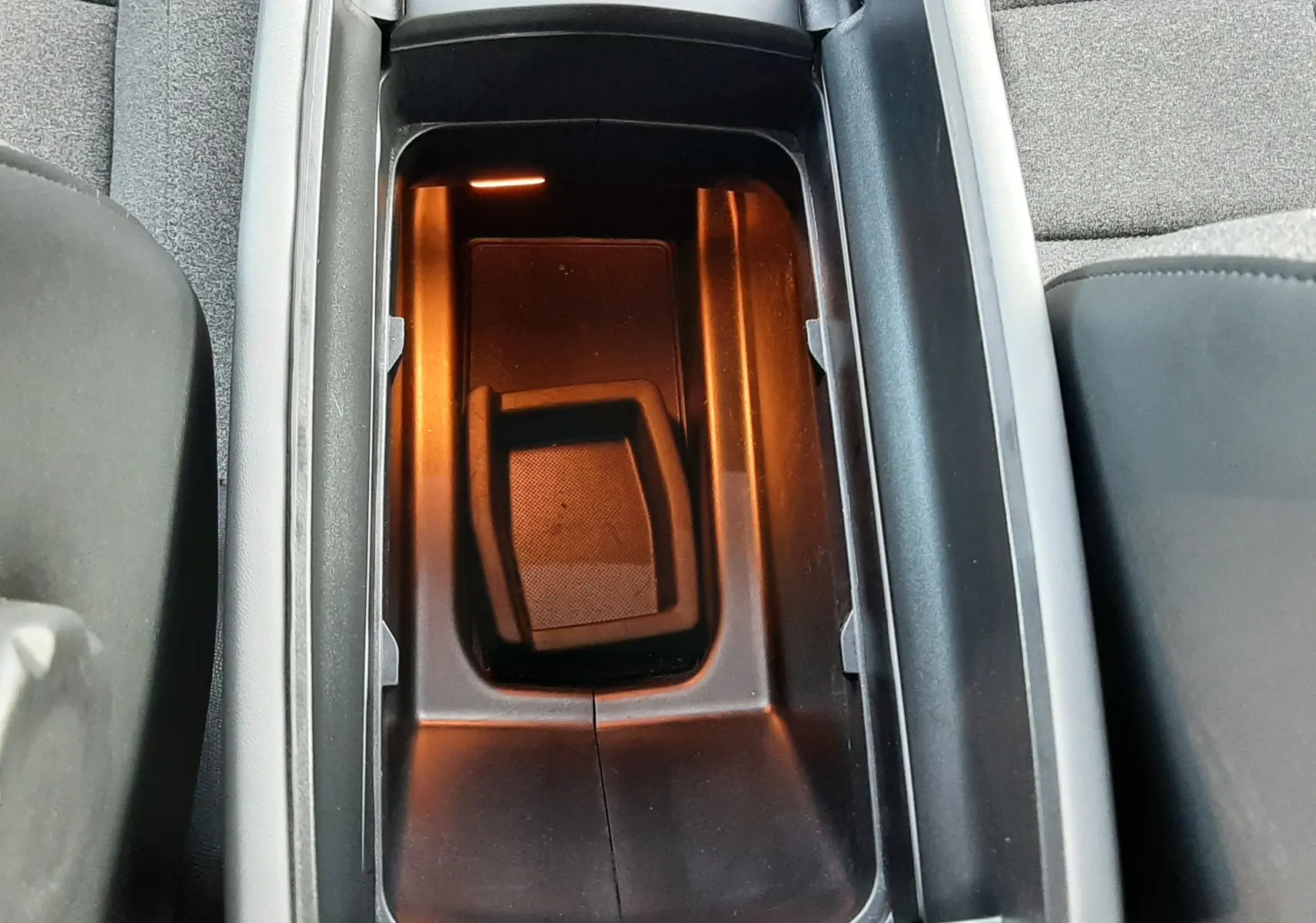 Vue plongeante sur le rangement central intérieur éclairé, entouré de sièges en tissu gris du Citroën C5 Aircross 2021.