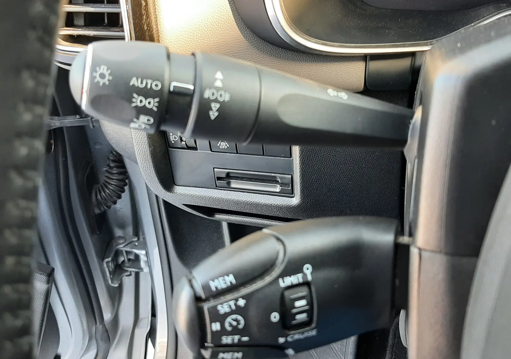 Gros plan sur les commandes au volant du Citroën C5 Aircross gris Artense, montrant les leviers de régulateur et d'éclairage.