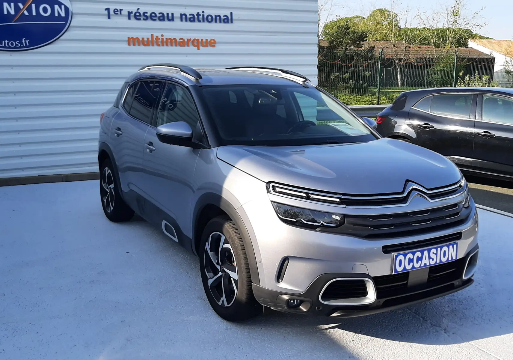 Citroën C5 Aircross gris Artense en 3/4 avant droit, avec jantes alliage et toit noir brillant visible.