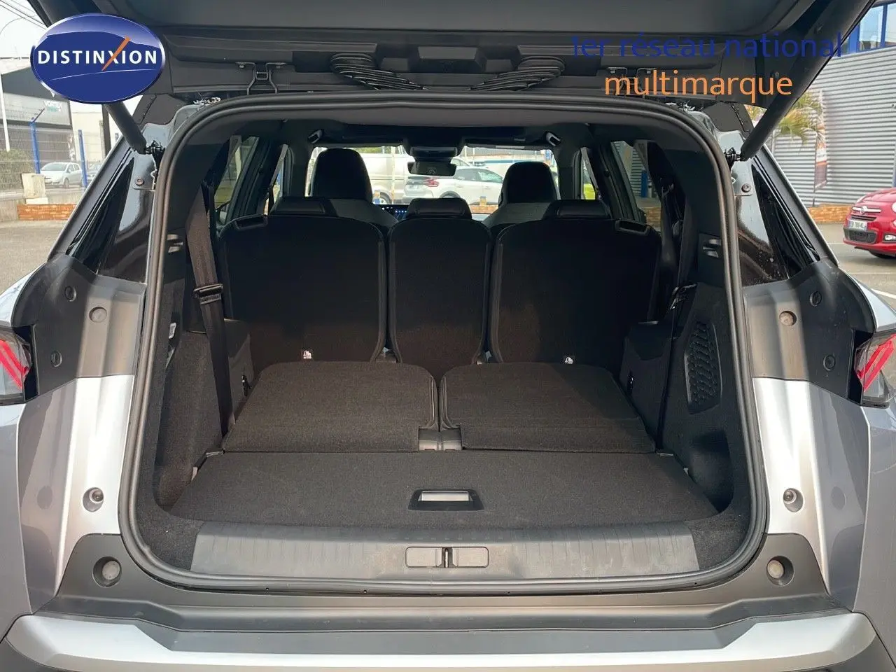 Coffre ouvert d'un Peugeot 5008 Hybrid gris Artense métal avec toit noir, vue arrière montrant les sièges rabattus.