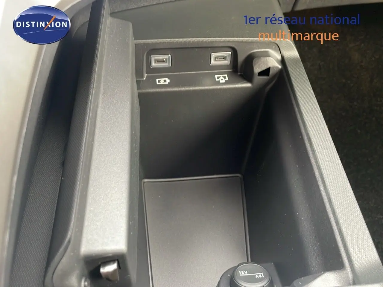 Vue rapprochée de la console centrale noire du Peugeot 5008 Hybrid 136ch GT 2025, montrant ports USB et prise 12V.