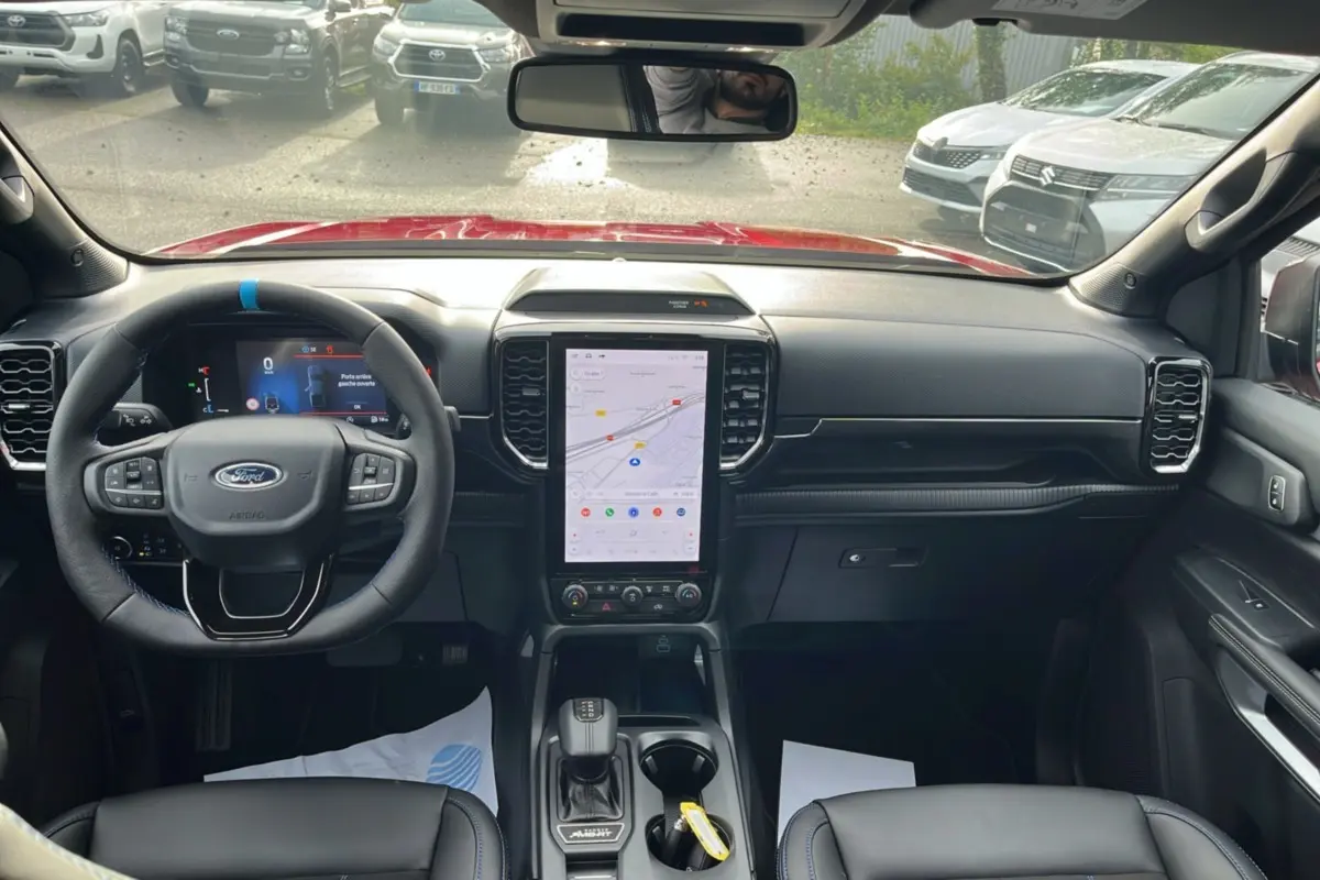 Vue intérieure avant du Ford Ranger 3.0 V6 240 MS-RT PLUS avec tableau de bord noir et écran tactile central vertical.