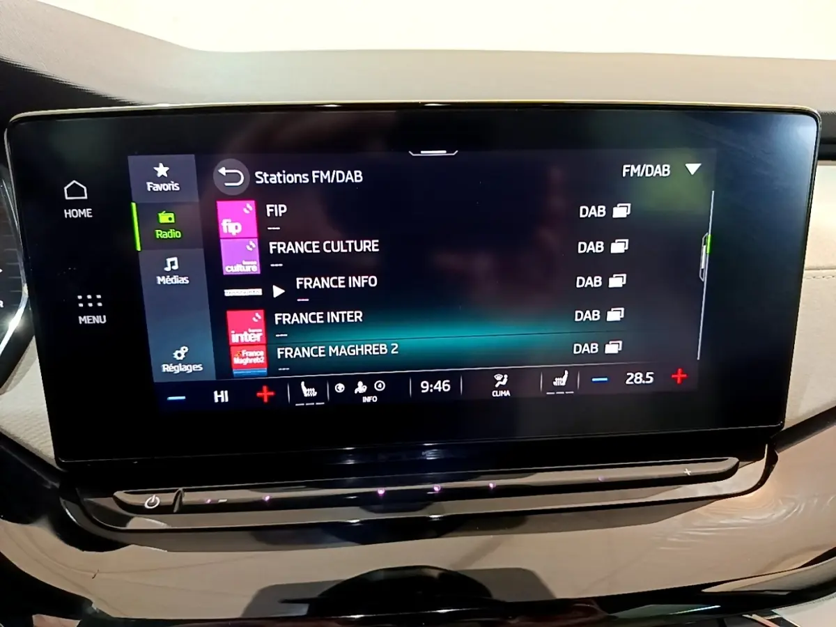 Écran tactile central affichant les stations radio FM/DAB dans l'habitacle beige de la Skoda Octavia blanche 2022.