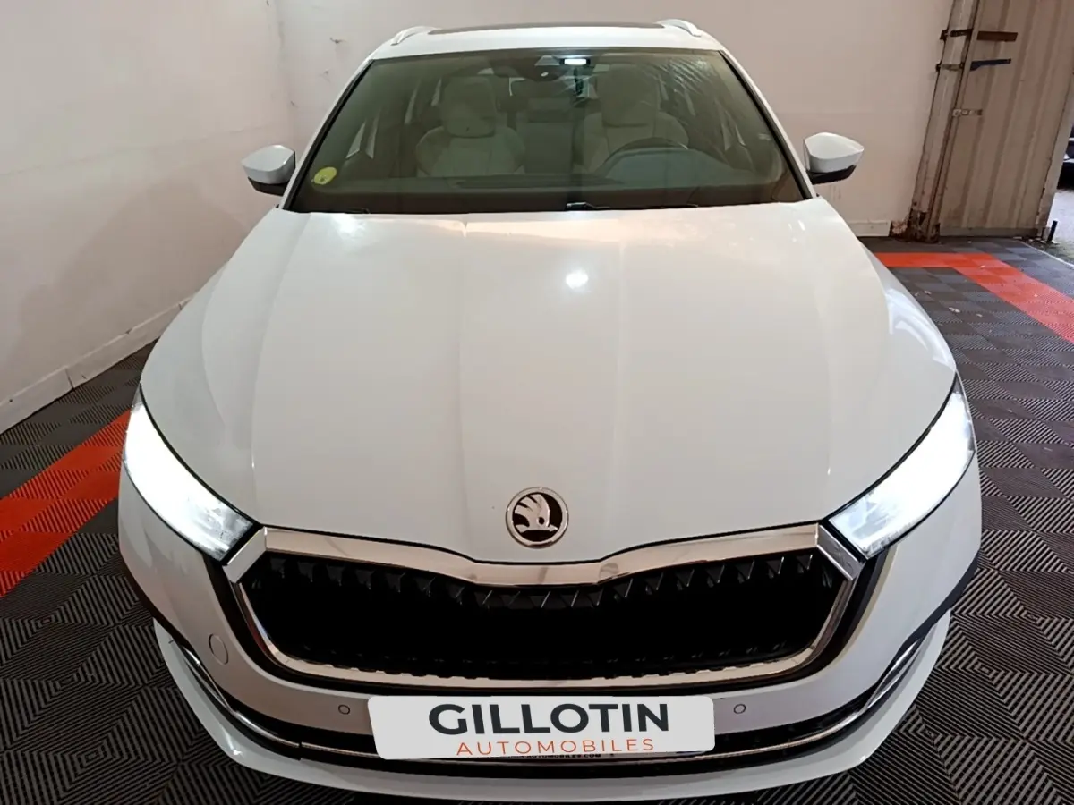 Vue avant d'une Skoda Octavia blanche 2022 avec phares LED allumés et calandre noire chromée