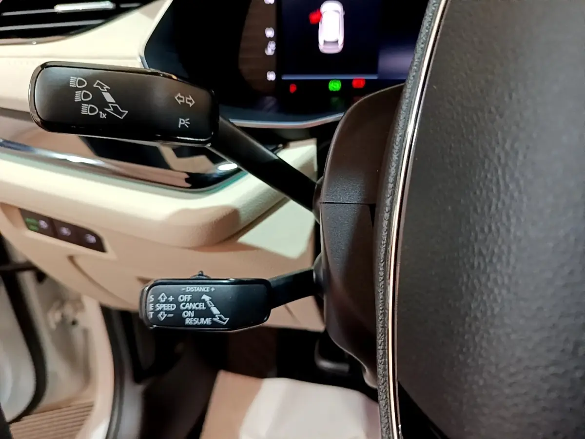 Gros plan sur les commandes de clignotants et régulateur au volant cuir noir de la Skoda Octavia blanche 2022.