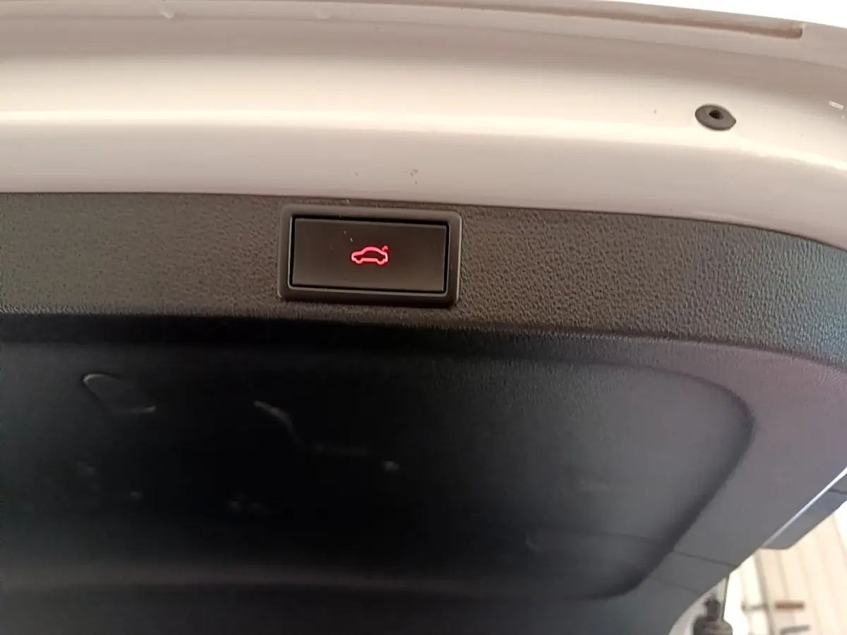 Bouton d'ouverture du coffre rouge sur la garniture intérieure blanche d'une Skoda Octavia 2.0 TDI 2022.