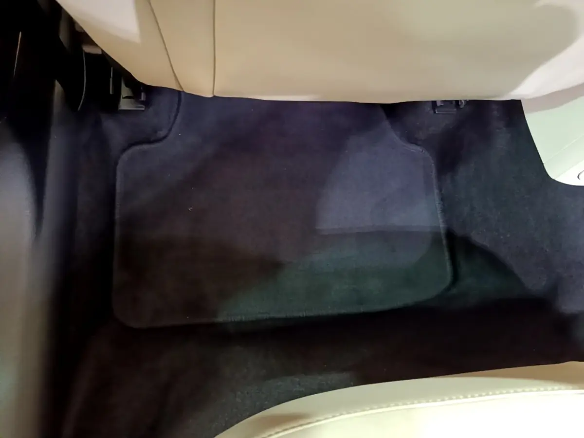 Vue rapprochée du tapis de sol noir sous le siège avant beige d'une Skoda Octavia blanche 2022.