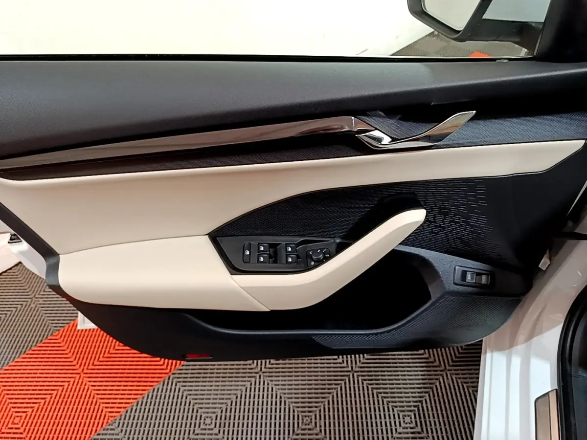 Vue intérieure du panneau de porte côté conducteur blanc et beige avec commandes électriques sur Skoda Octavia 2022.