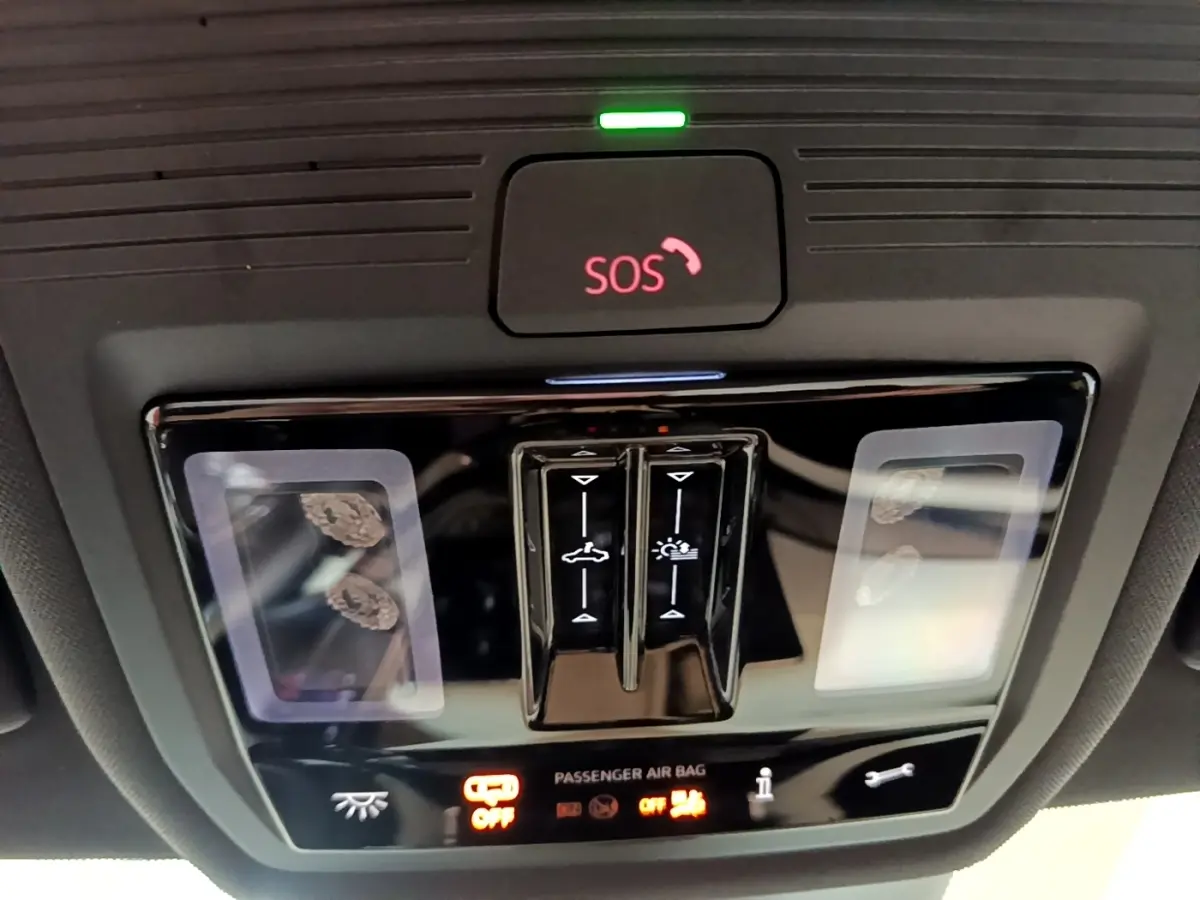 Gros plan sur la console de plafonnier noire avec bouton SOS rouge et commandes d’éclairage dans une Skoda Octavia blanche 2022.