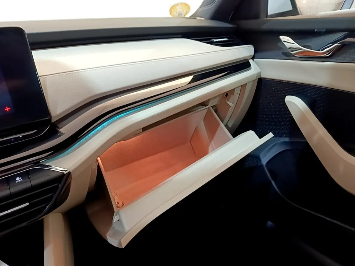Intérieur beige clair de la Skoda Octavia 2022, vue sur la boîte à gants ouverte côté passager avec éclairage ambiant bleu.