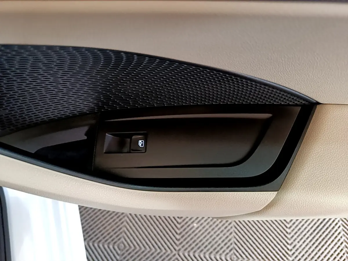 Gros plan sur la commande de lève-vitre côté conducteur dans l'intérieur beige d'une Skoda Octavia 2022 blanche.