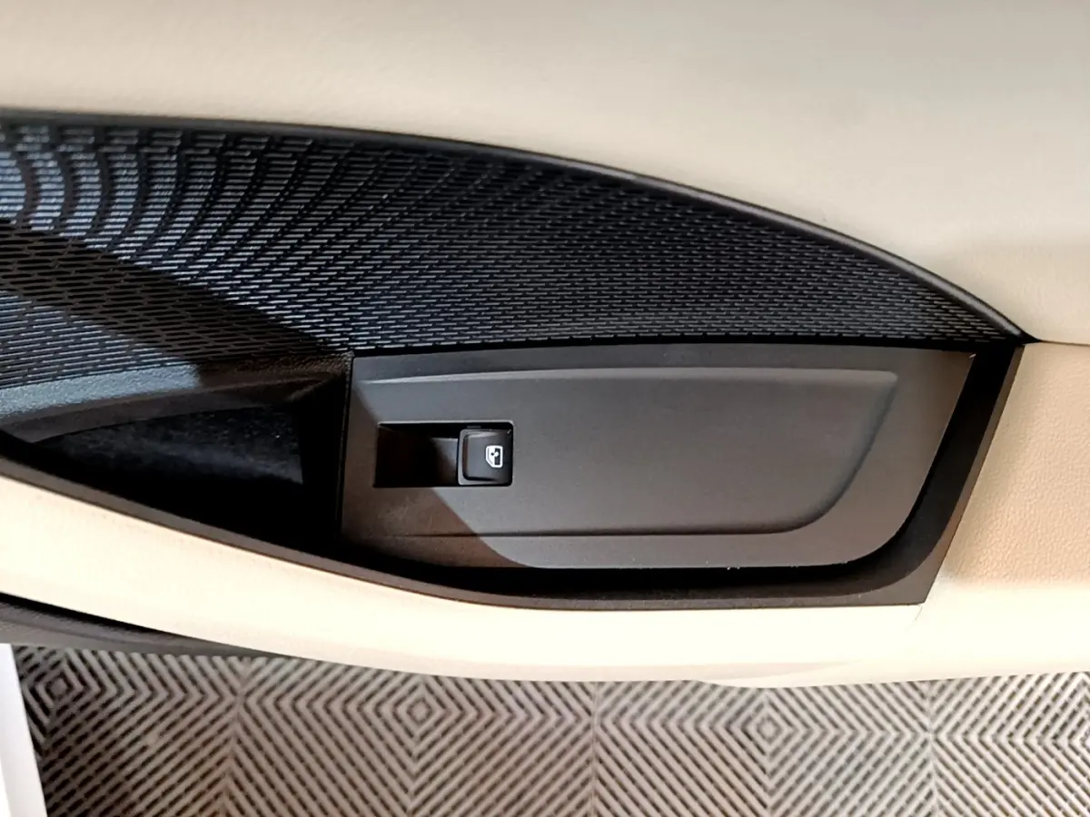 Gros plan sur la commande de verrouillage de porte noire intégrée dans la garniture beige intérieure d'une Skoda Octavia blanche.