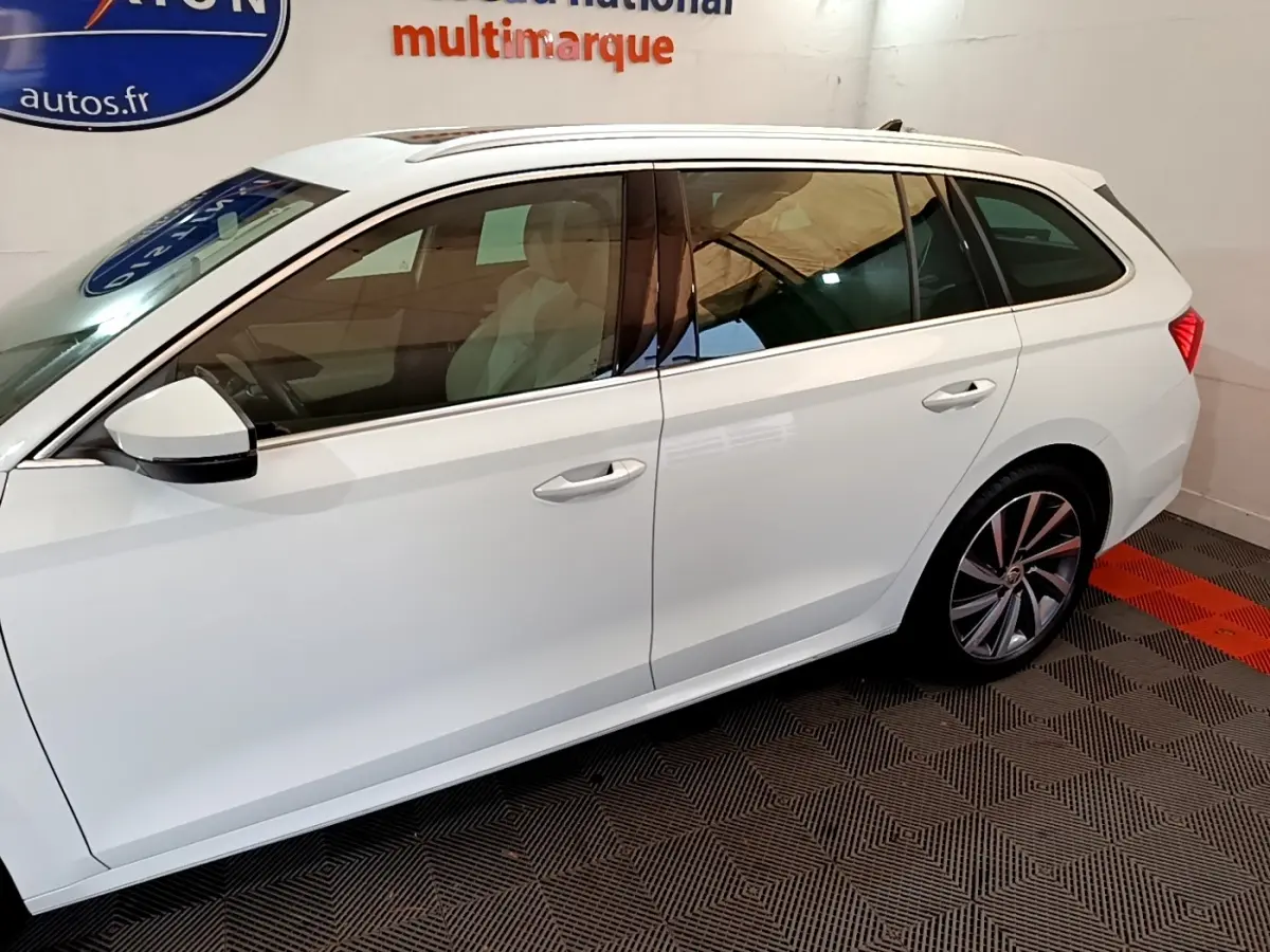 Vue latérale côté gauche d'une Skoda Octavia break blanche avec jantes alliage et vitres teintées.