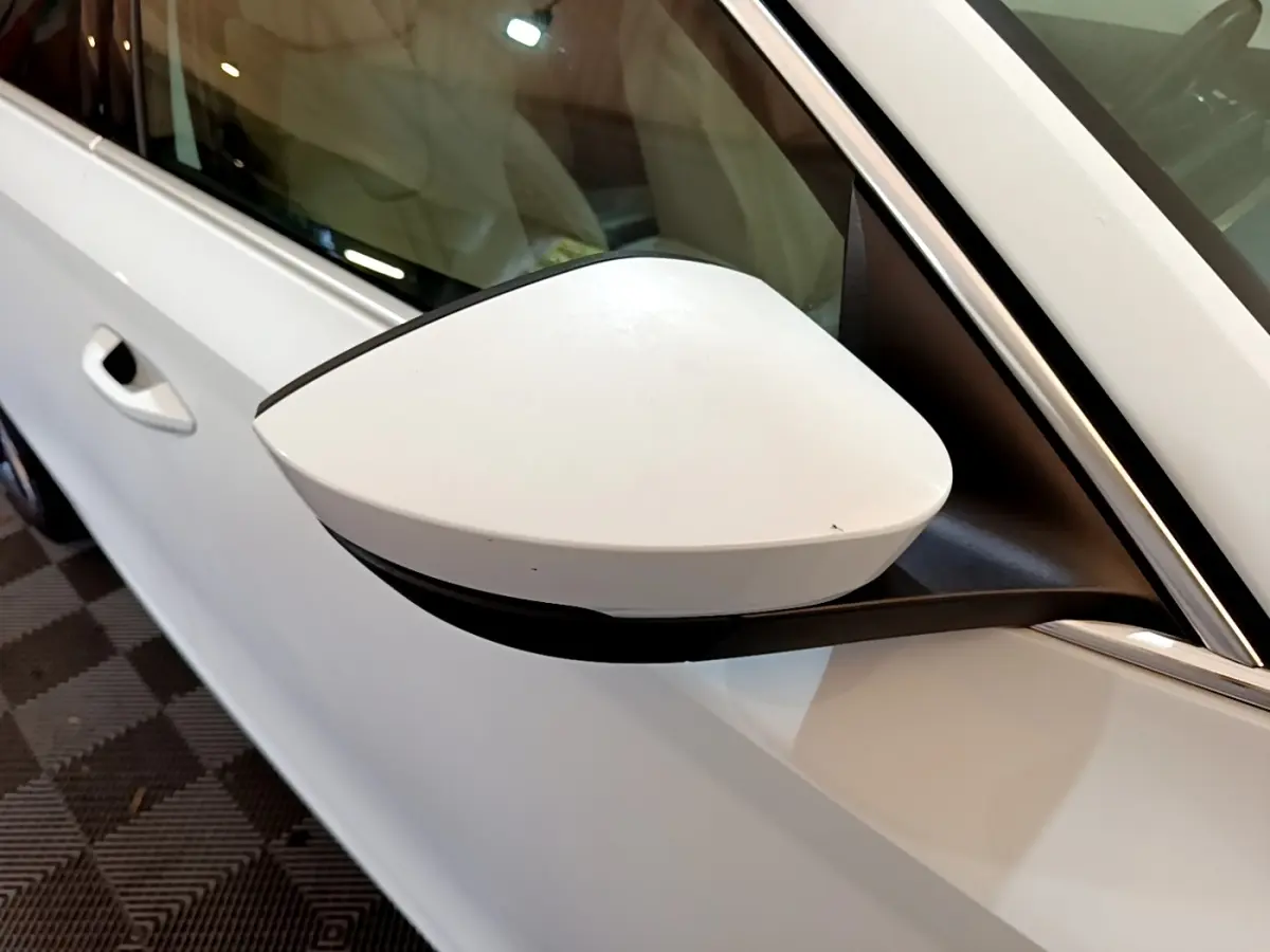 Rétroviseur blanc côté gauche d'une Skoda Octavia 2.0 TDI 150 DSG7 Style 2022, vue rapprochée sur porte et vitre.