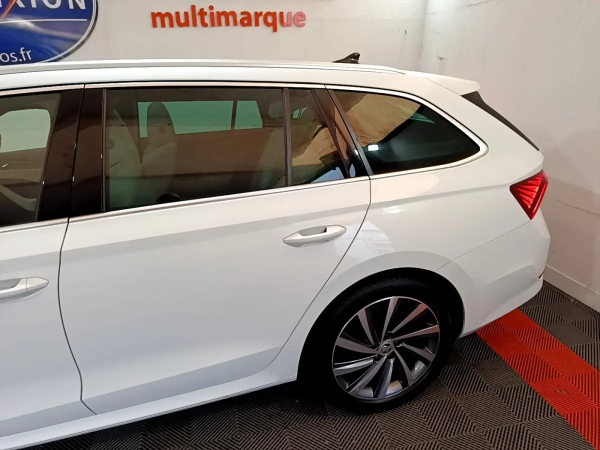 Vue latérale côté droit d'une Skoda Octavia blanche, mettant en valeur la roue arrière et la lunette teintée.
