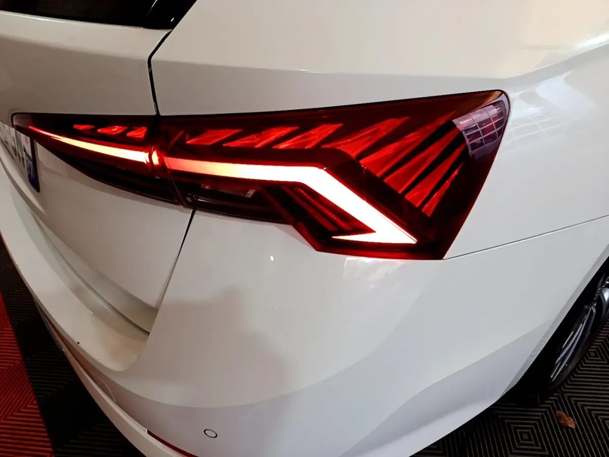 Gros plan sur le feu arrière droit allumé d'une Skoda Octavia blanche, soulignant ses lignes LED distinctives.